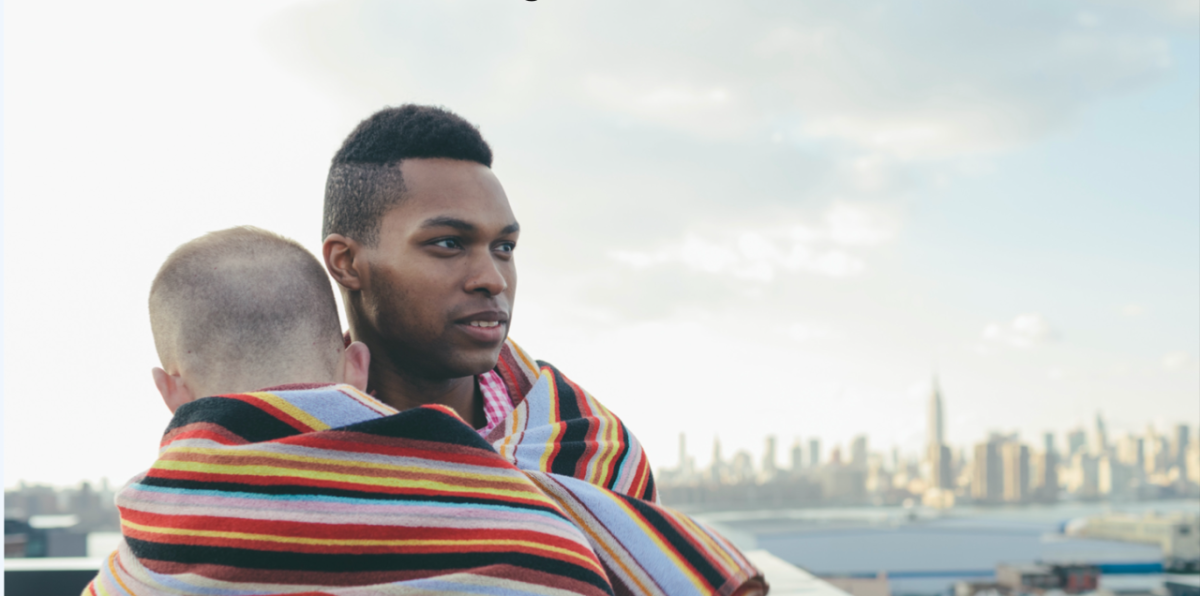 two people standing close together in front of cityscape, wrapped in one scarf