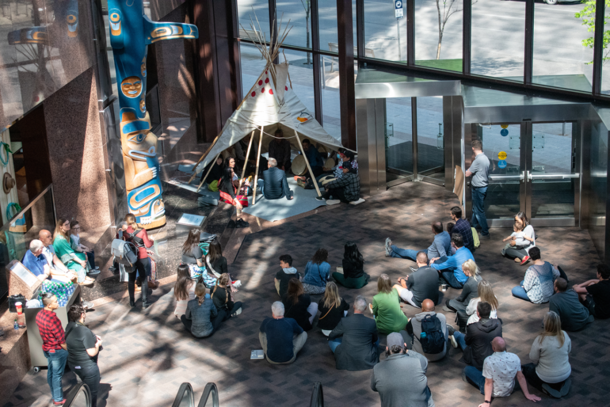 People seated in and around a teepee
