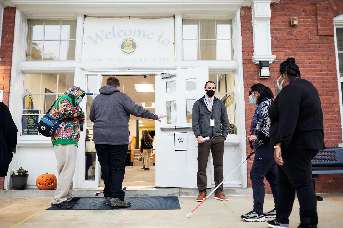 students using white canes entering a school building