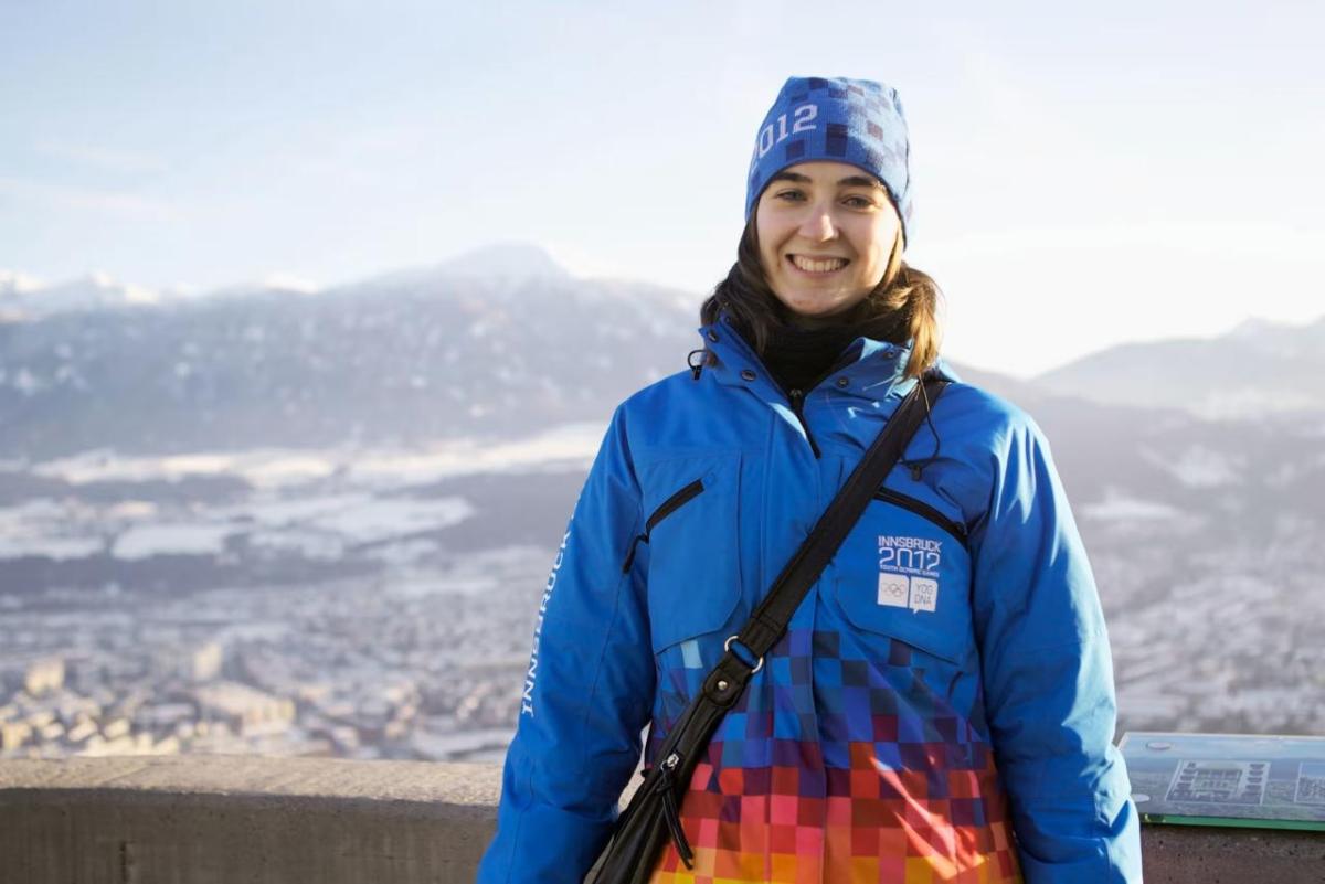 Smiling woman wearing hat and jacket reading "Innsbruck 2012"