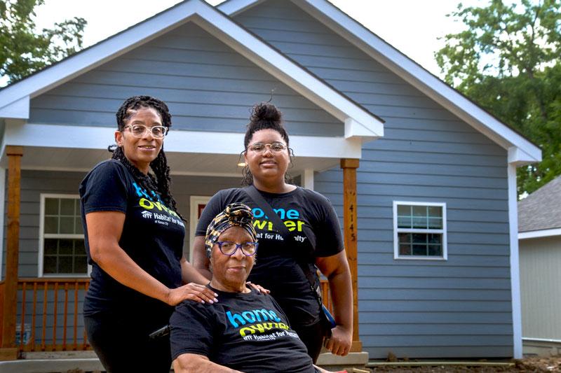 Janetta and two family members outside their new home.