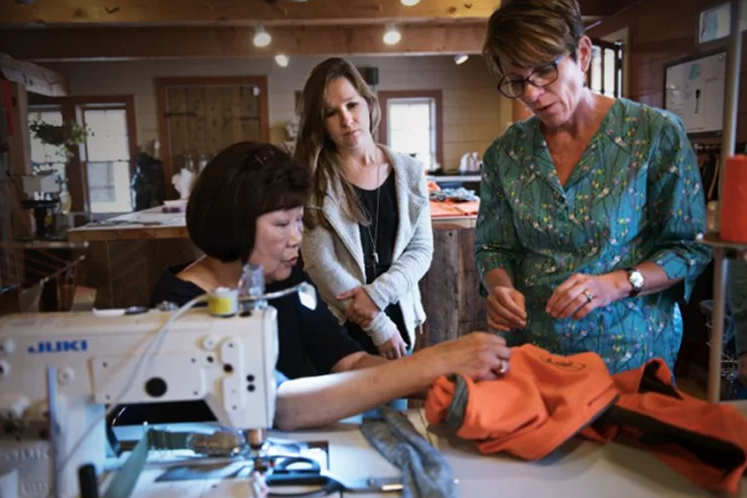 3 people look at a garment being put together