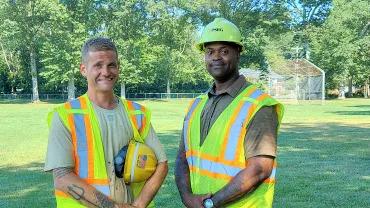 Jonathan Harmon and Eric Adams, both outside wearing safety vests