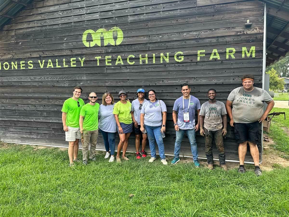 Group of volunteers stood outside of a 'Jone Valley teaching farm' building