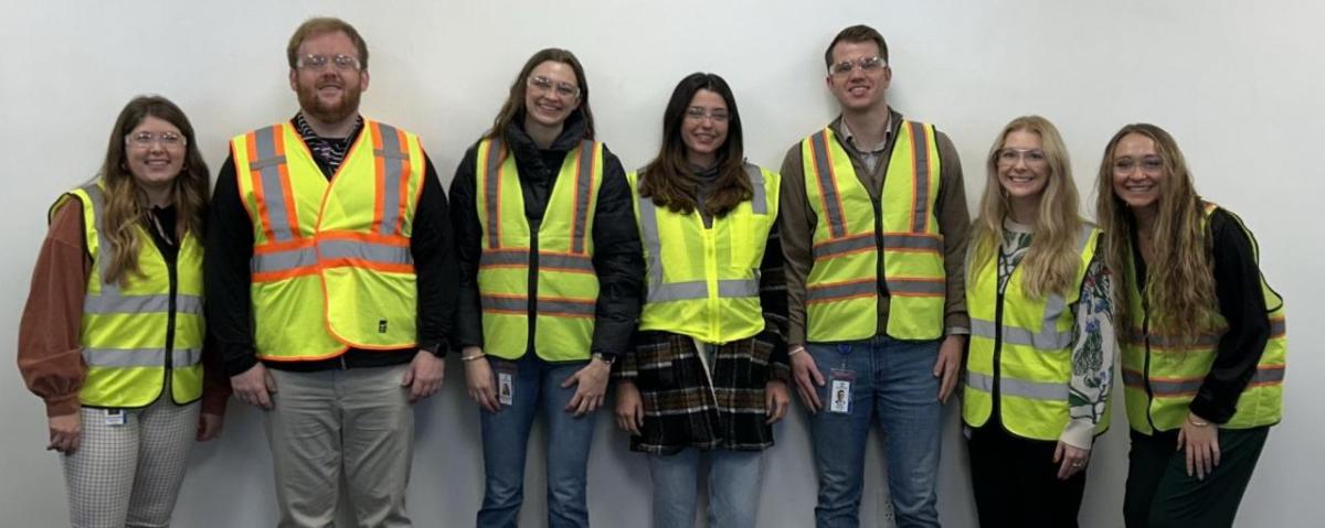 People wearing hi-vis vests while stood in a line against a wall