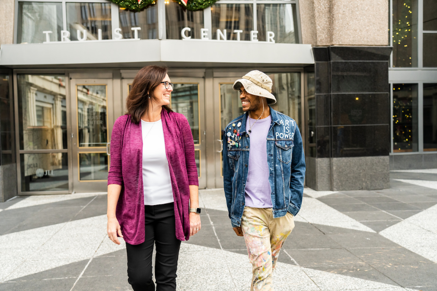 Two people walking out of a building smiling at each other