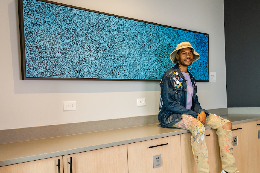 Person sat on a counter top next to a piece of art