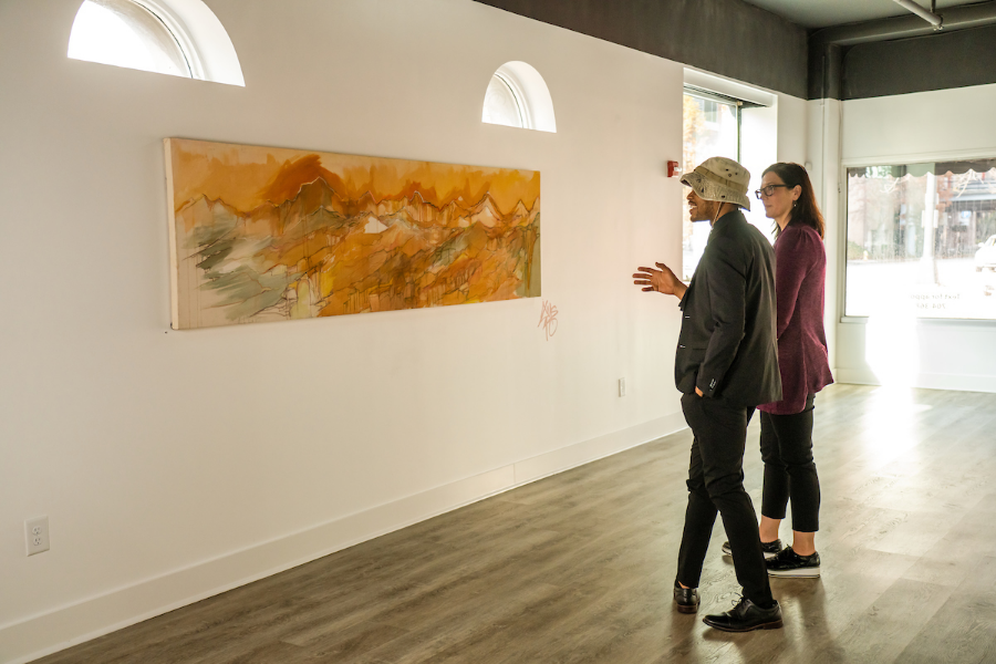 Two people stood up looking at a piece of art on the wall