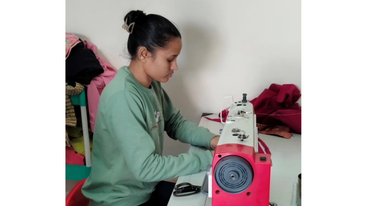 Jyoti sat at a desk using a sewing machine 