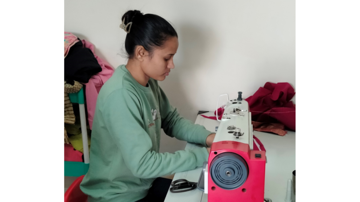 Jyoti sat at a desk using a sewing machine