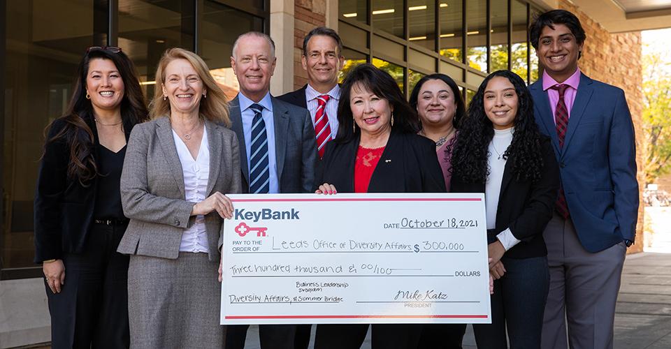 Group of people from Leeds School of Business and KeyBank are holding a check for $300,000. There are 5 women and 3 men in the group.