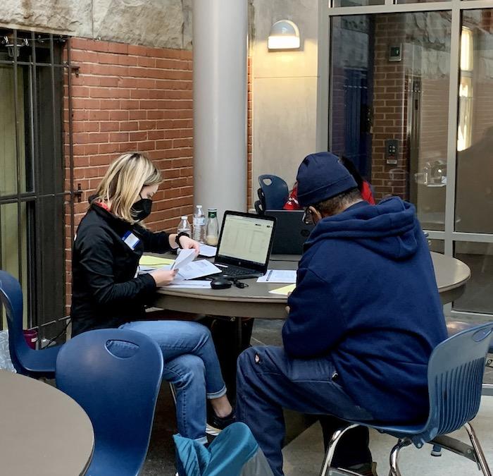 KeyBank volunteer seated with a individual and helping him prepare his tax return. 