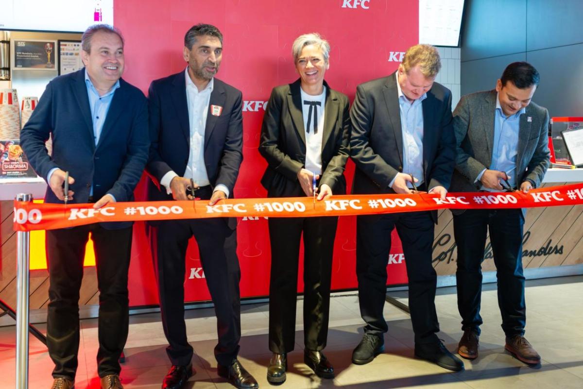 Five people standing behind a ribbon with scissors.