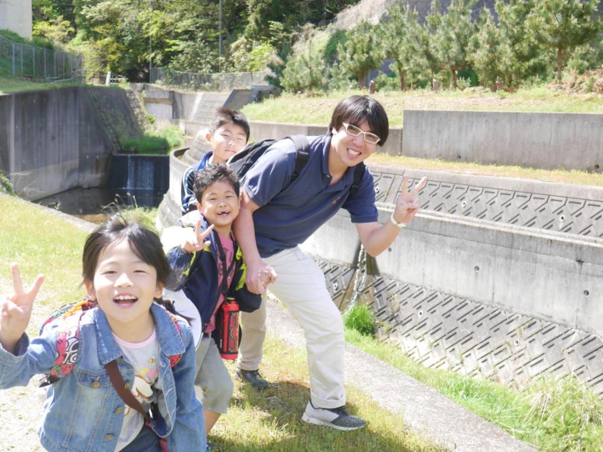 Kobe Jitsugyo Gakuin children and an adult smiling on a field trip