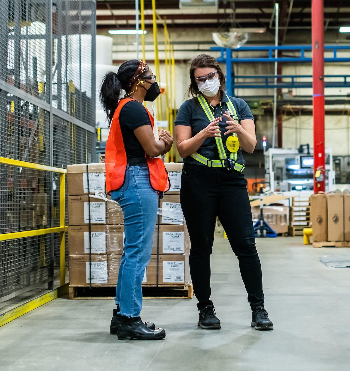 Two female manufacturing employees speaking to each other on the shop floor