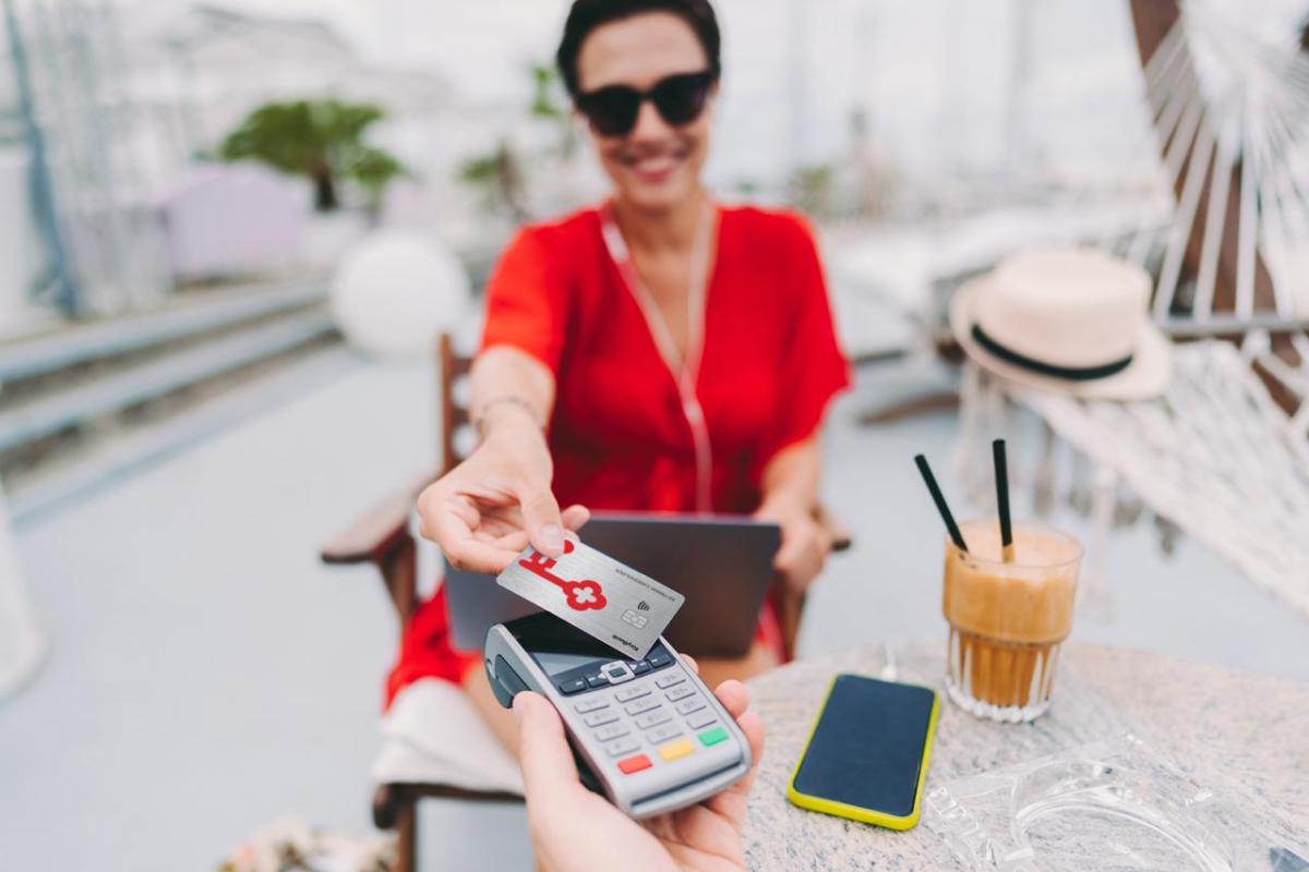 Person at a cafe presenting a KeyBank secured card for payment.