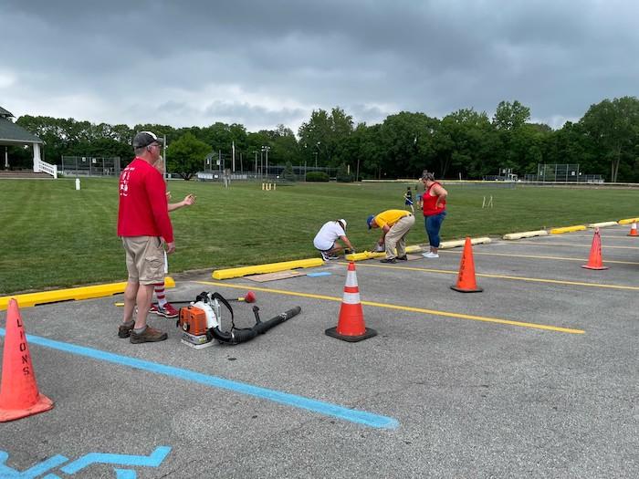 KeyBank volunteers painting barriers in a parking lot for a park.