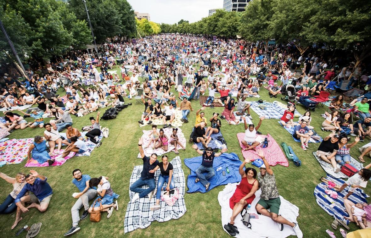 Lots of people sitting on blankets in a field