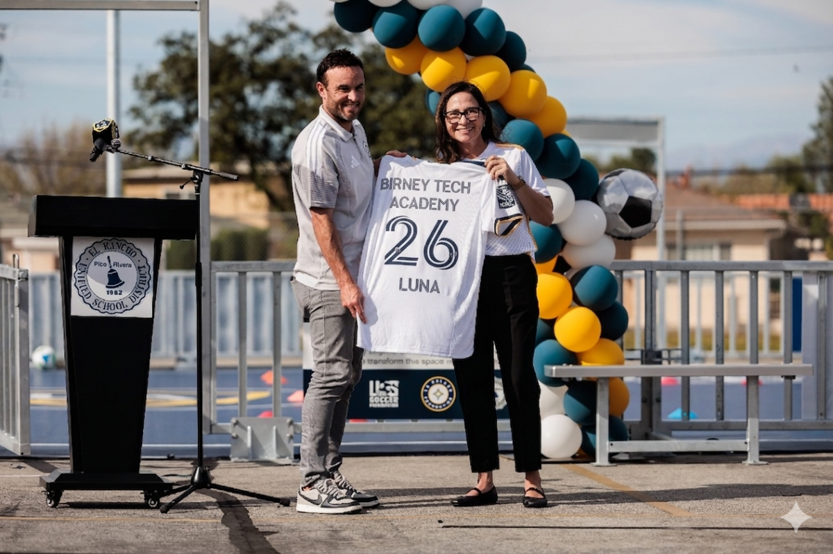 LA Galaxy legend Landon Donovan and an official holding a custom "Birney Tech Academy" jersey.