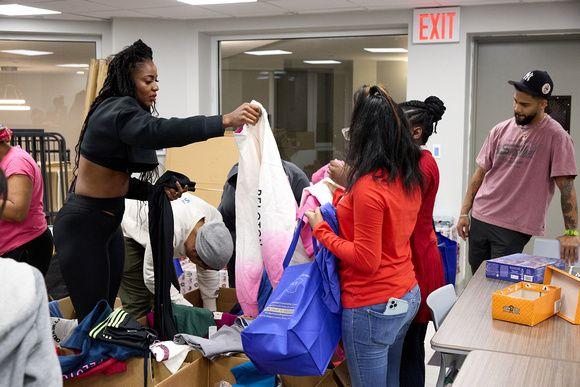 A person hands a large bag to others, small group of people looking through boxes.