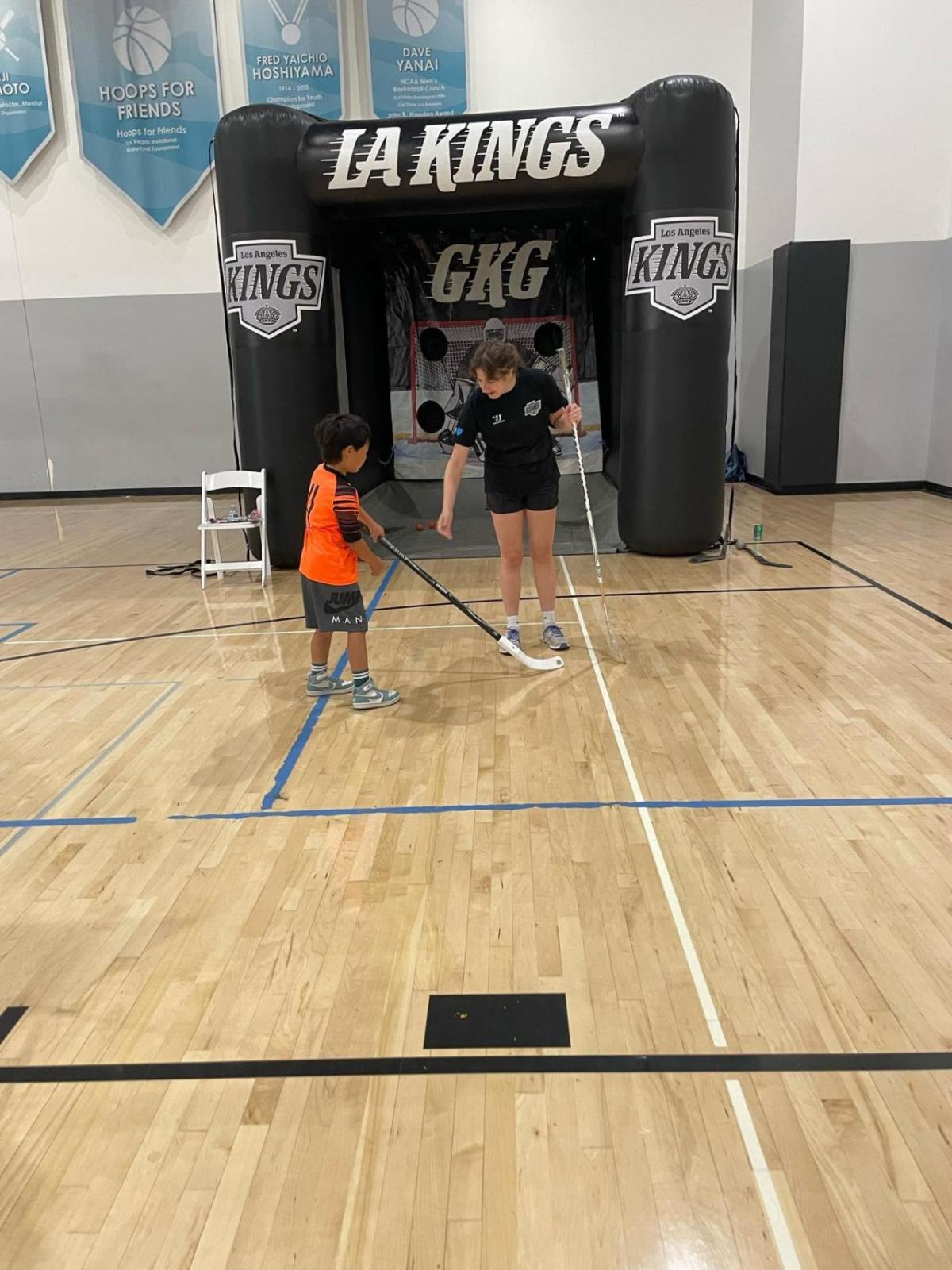 Representatives from LA Kings Hockey Development teaching a child  hockey puck shoot