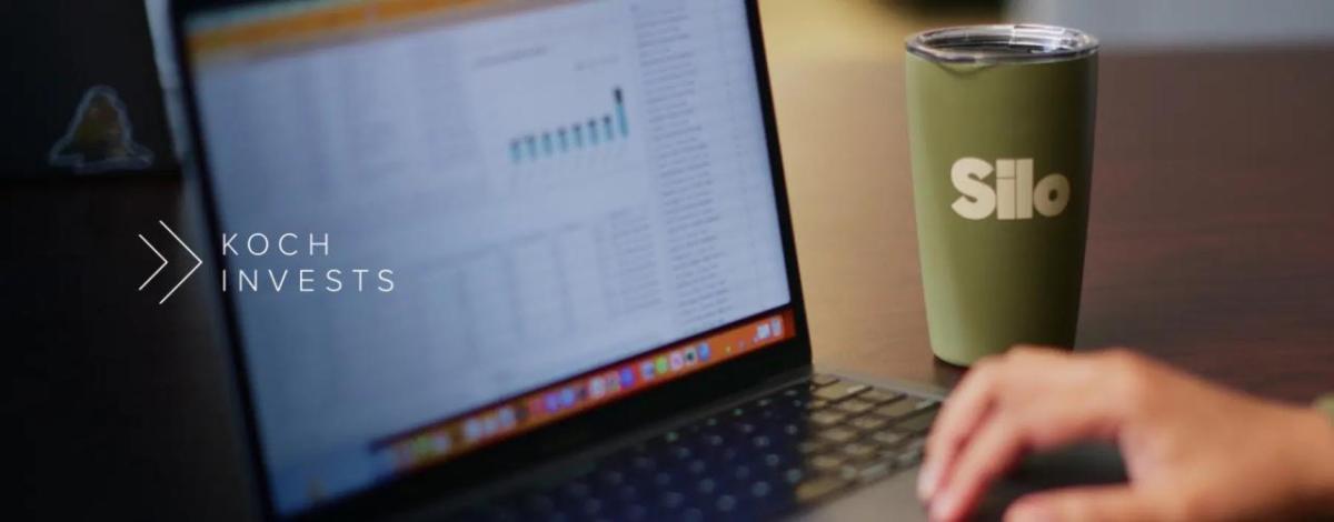 Close up of a person using a laptop, with a Silo travel mug placed to the right-hand side of the laptop