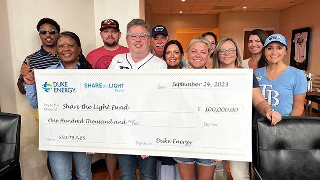 Groupd of people smiling while holding a cheque for $100,000