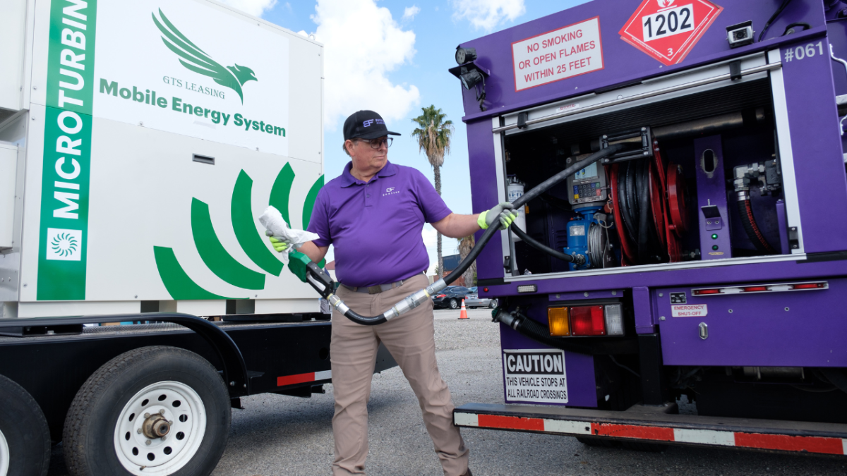 A Booster service provider holds the nozzle from Booster tanker near a mobile energy solution.