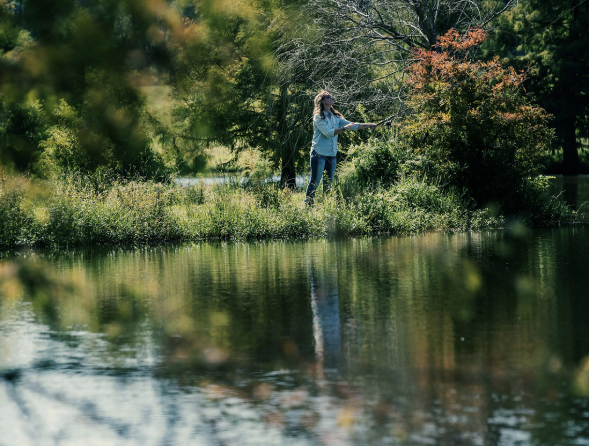 Person stood at the side of a river looking at the trees