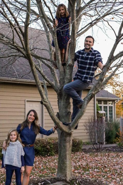 Lynn Moersch with her family outside, a child and adult are sitting in a tree