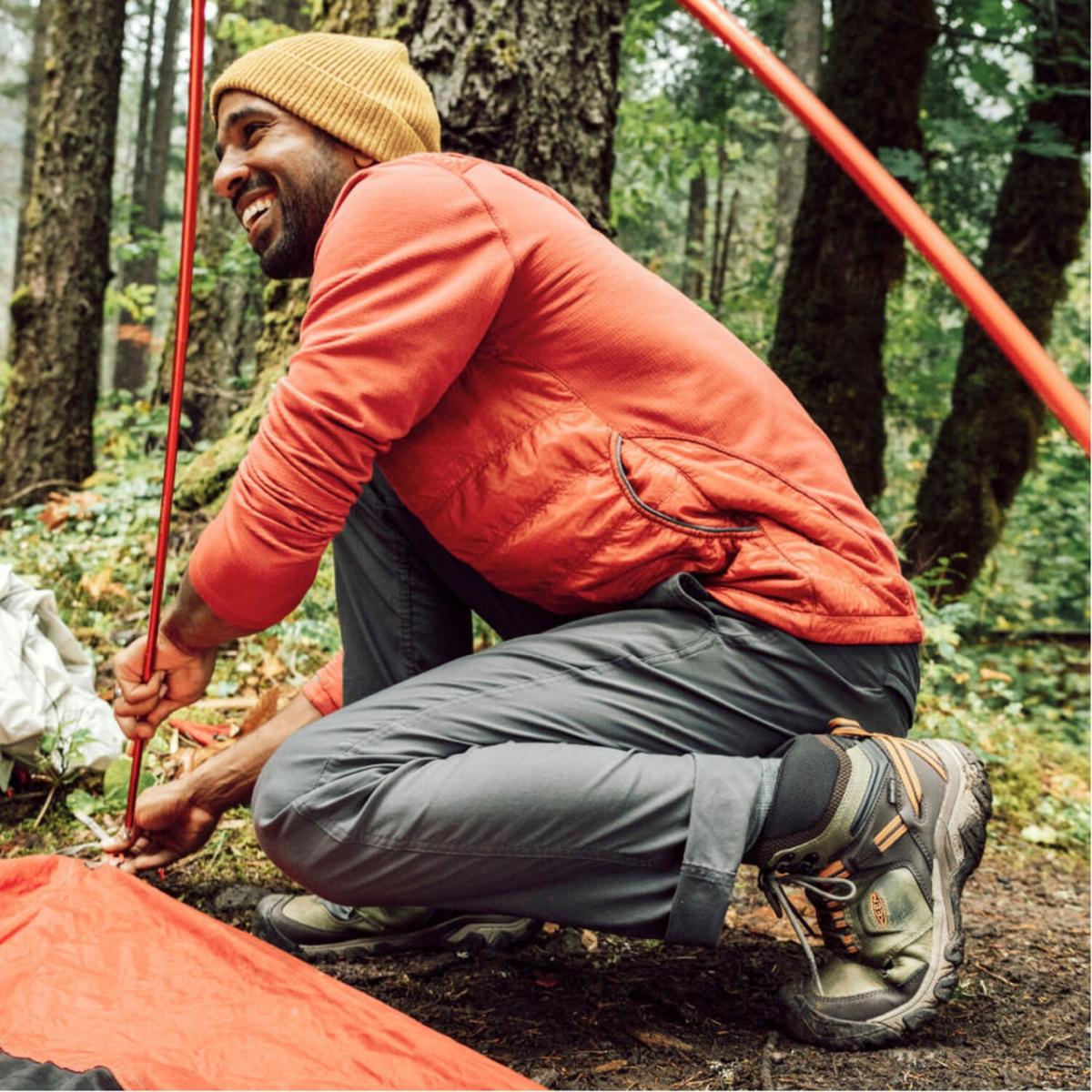 Ridge Flex Mid WP Person in orange jacket setting up a tent in the woods