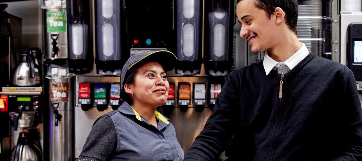 Female and male staffers smiling at each other. 