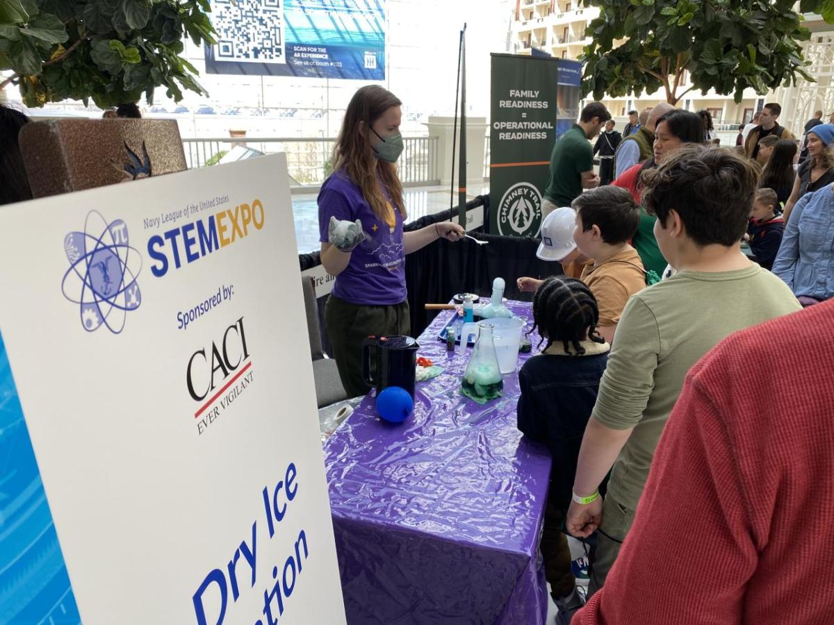 A presenter does a science experiment for onlookers.