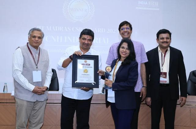 Five smiling people posed, two holding a plaque.