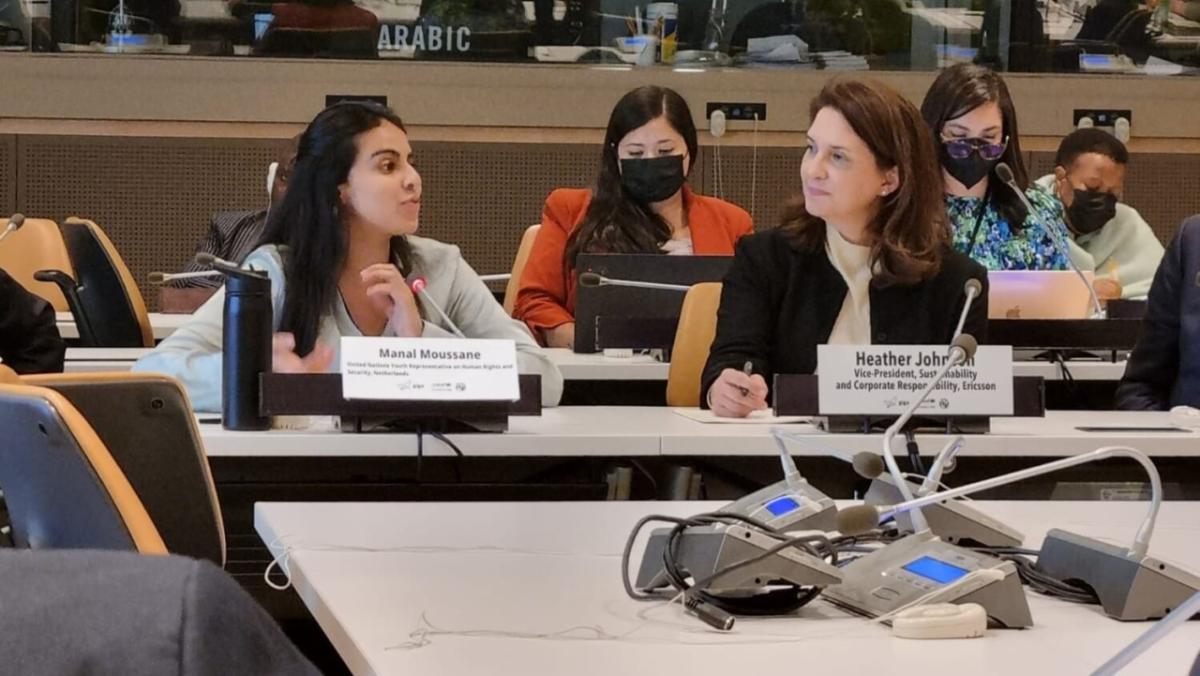 Manal Moussane seated next to Heather Johnson at a long table, other members at a table behind them.