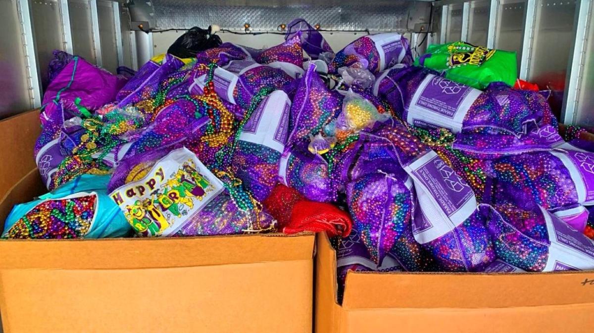 Entergy again funds Mardi Gras recycling initiative. Dozens of bags of mardi gras beads with recycle image and "Happy Mardi Gras" printed on them.