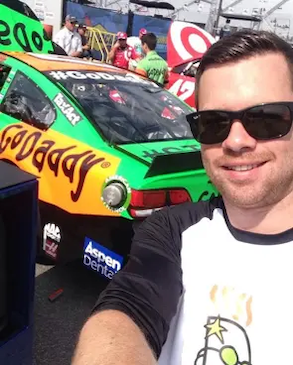 Mark shown in front of a GoDaddy sponsored NASCAR.