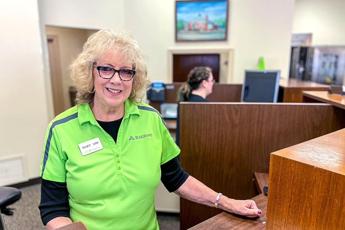 Mary Lou Schlueter in a green shirt at a teller's station