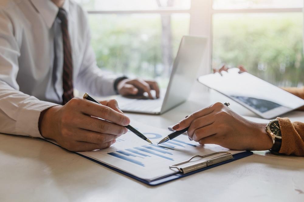 two hands with pens pointing at a report