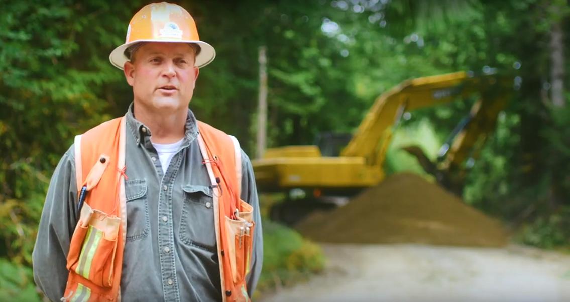 Matt Poppe in hard hat, a large machine behind them.