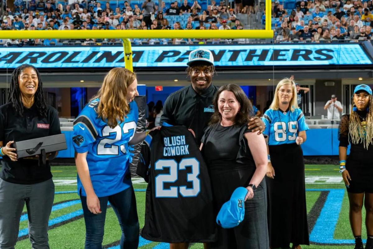 Megan Bornemann holding a custom jersey next to others on a football field.