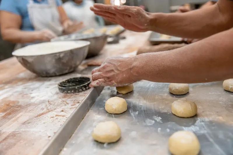 People rolling out dough balls.