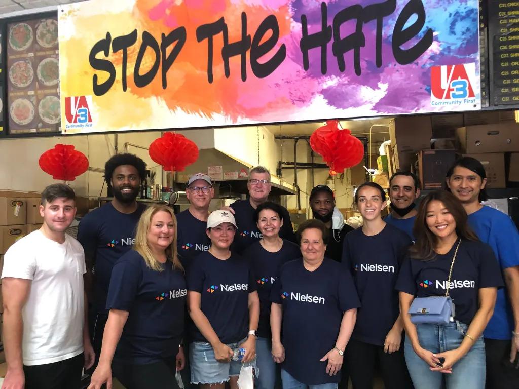 A group of people in an Asian restaurant, large "stop the hate" sign