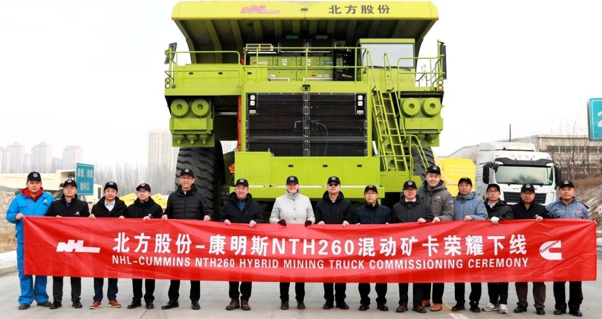 A line of people holding a line banner in front of a mining truck