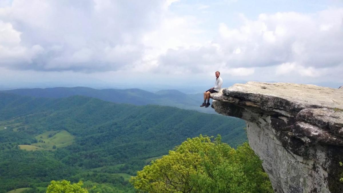 Man seated on the edge of a cliff.