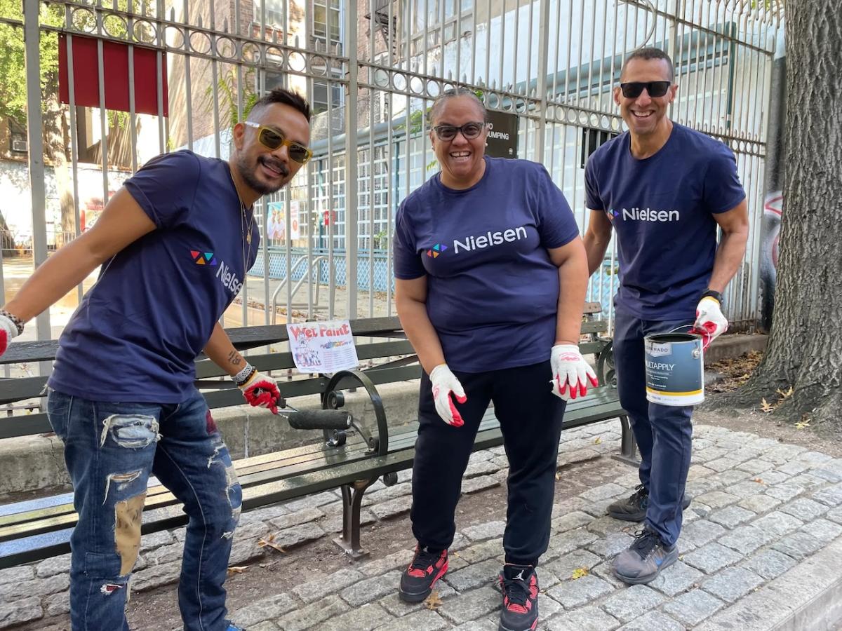 Nielsen NYC volunteers shown painting a bench.
