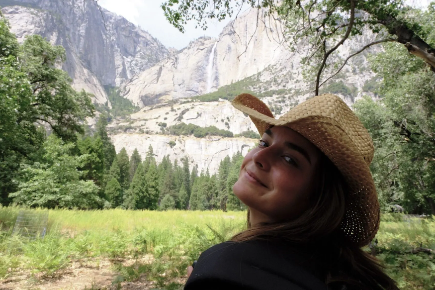 Natalie wearing a straw hat and looking at a canyon.