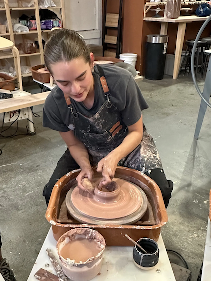 Natalie seated at a potters wheel.