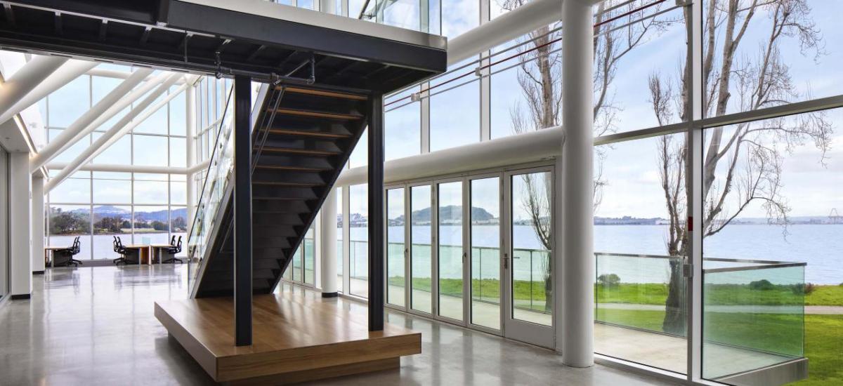 Interior of an office building with lots of windows and natural light. An open staircase central in the space.