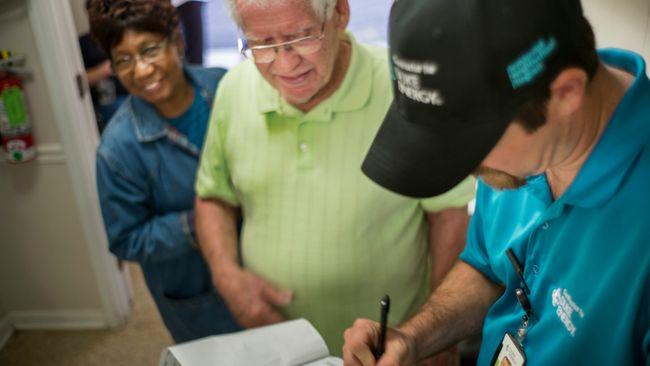 Two residents speaking with a Duke Energy employee who is taking notes on a clipboard